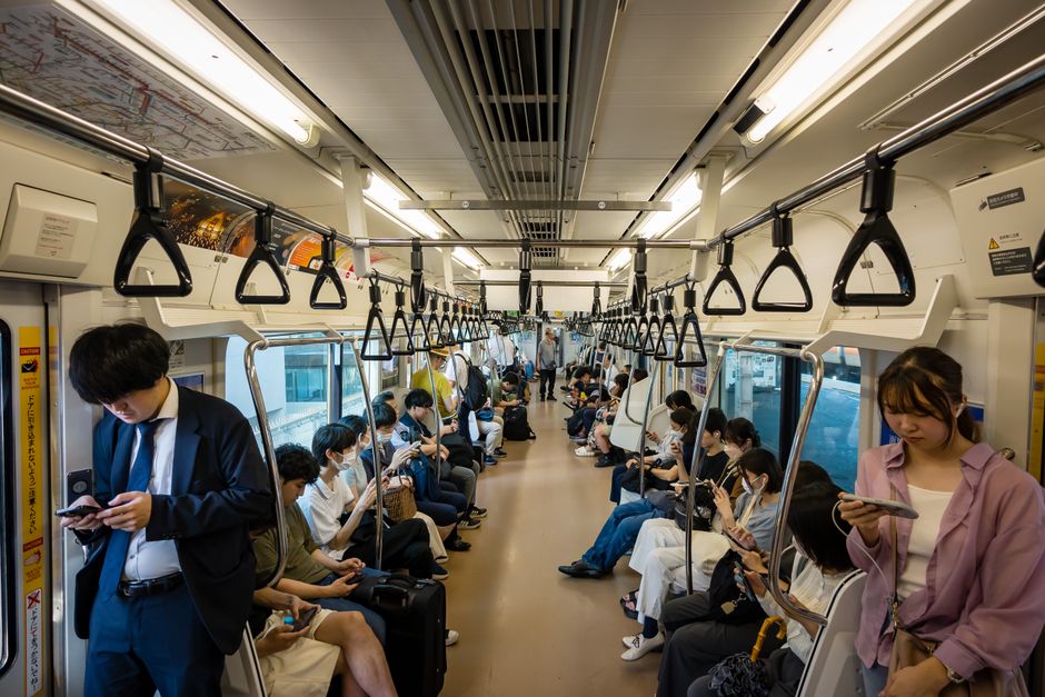 Passengers riding through the city in a bright commuter train carriage.