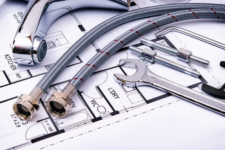 Drafting tools, rulers and compasses arranged across an architectural floor plan.