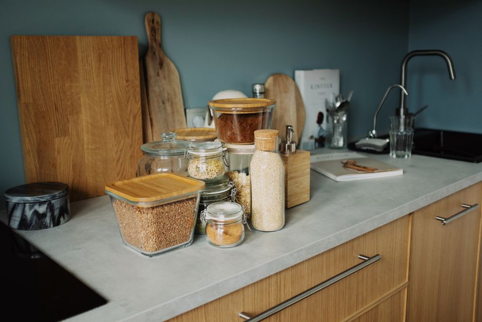 Glass jars filled with grains, pasta and dry ingredients arranged on pantry shelves.